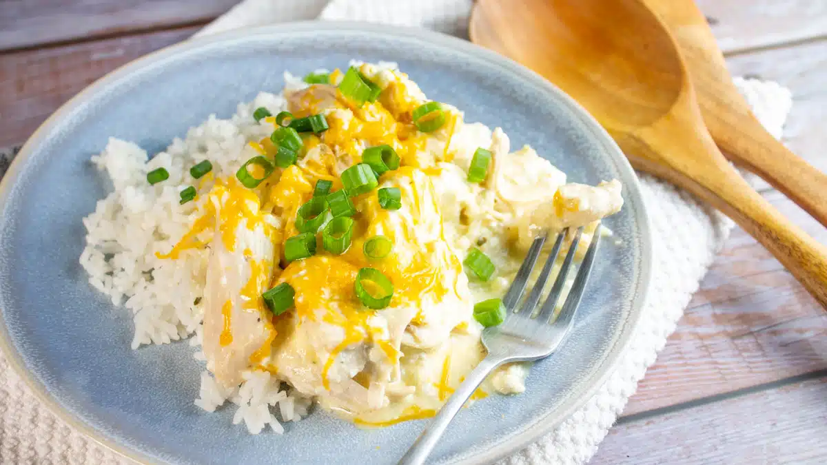 Wide image of slow cooker Ranch chicken over white rice.