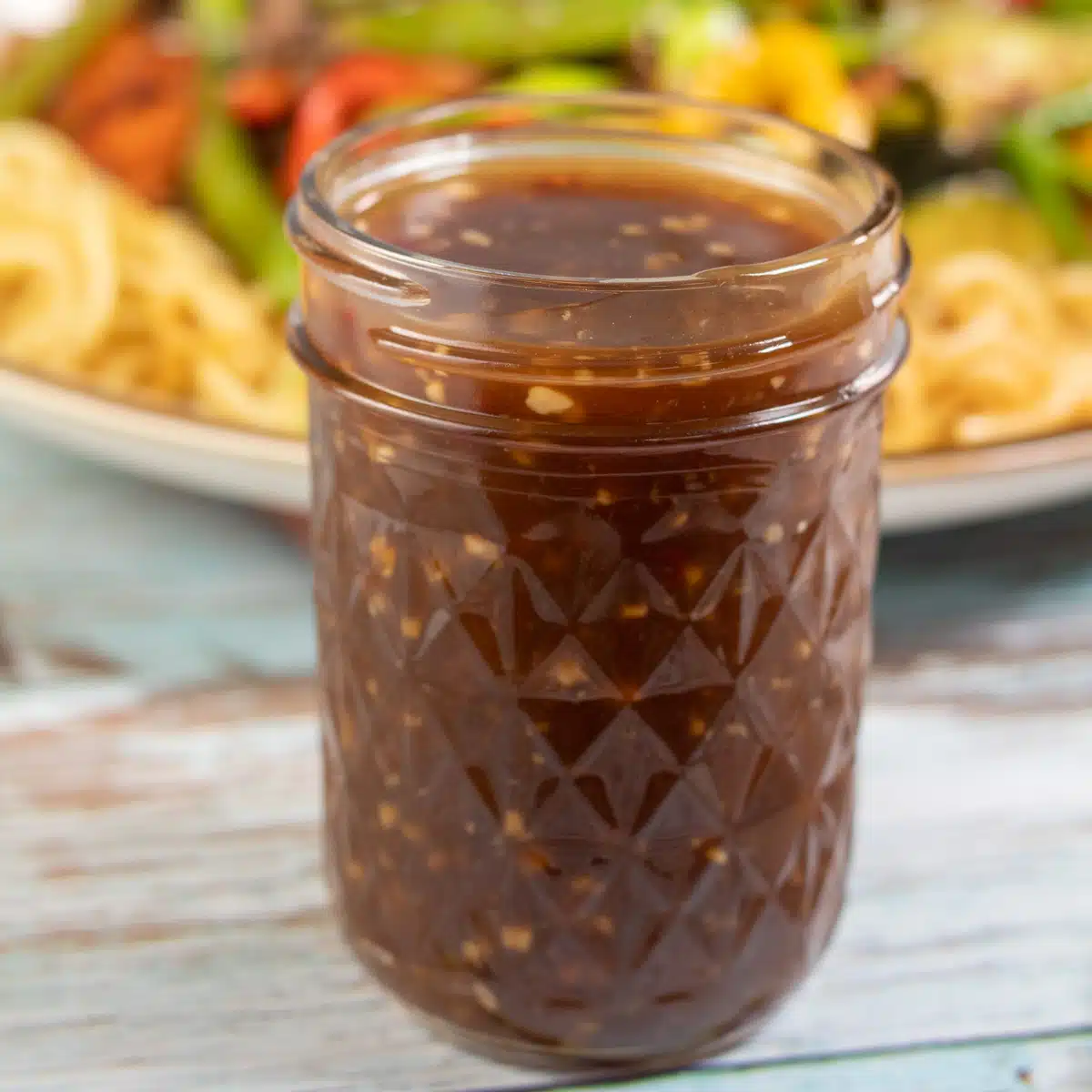 Square image showing a glass jar of stir fry sauce.