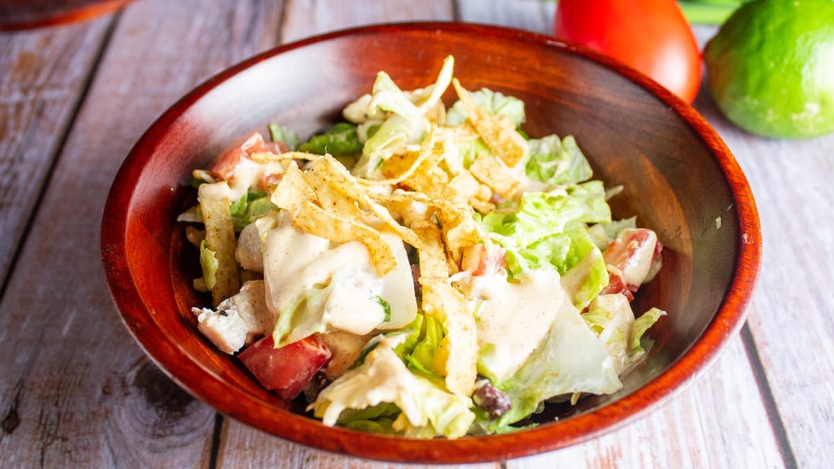 Wide image of a Tex-Mex salad in a wooden bowl.