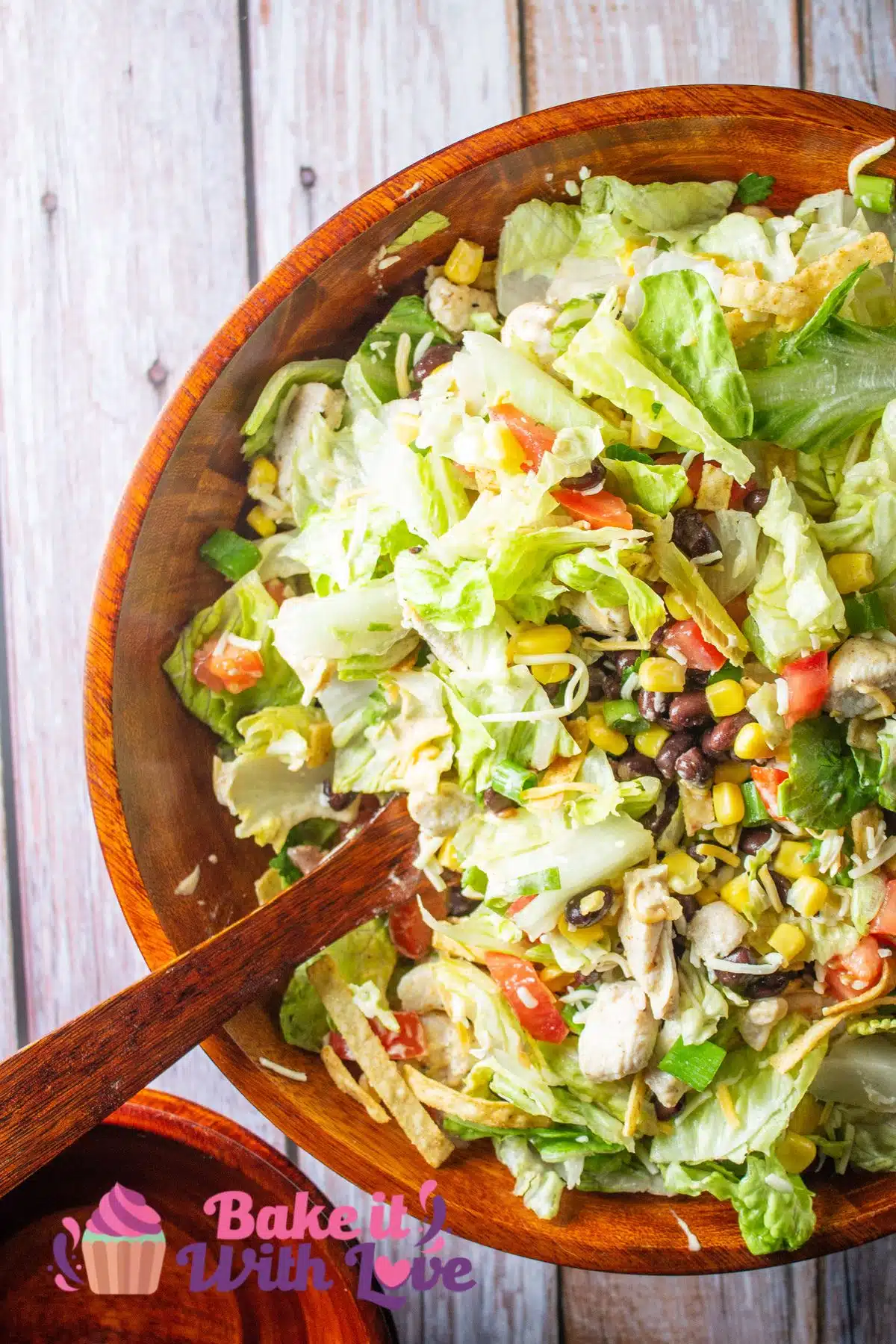 Tall image of a Tex-Mex salad in a wooden bowl.