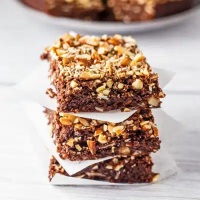 Square image of almond brownies neatly stacked.