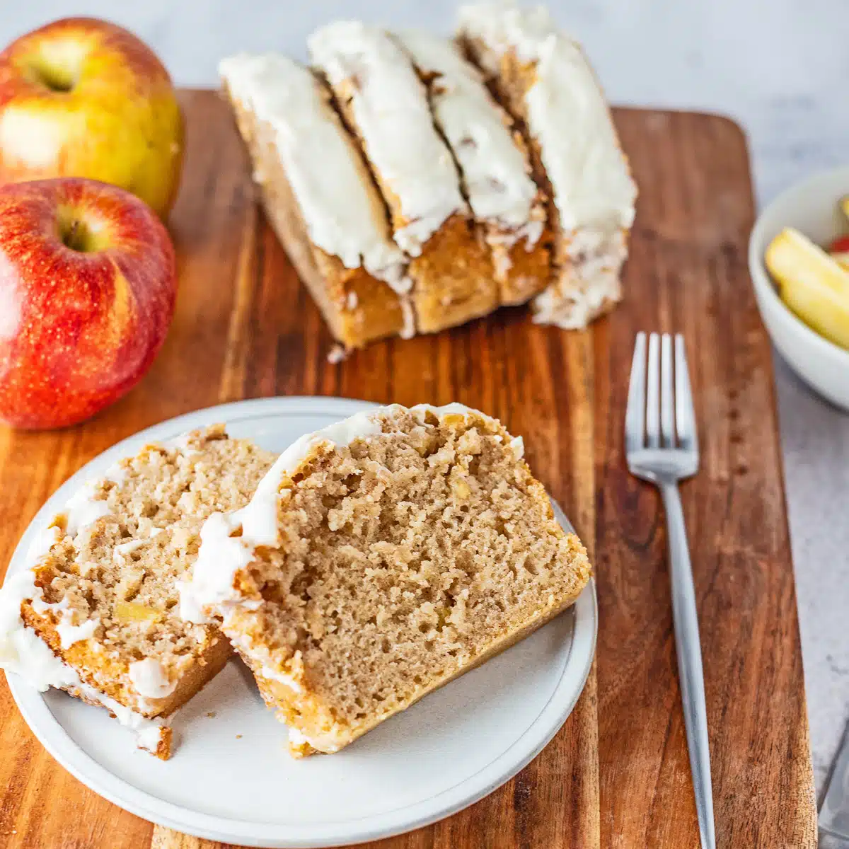 Gambar persegi roti apel kayu manis diiris dan di atas piring putih.