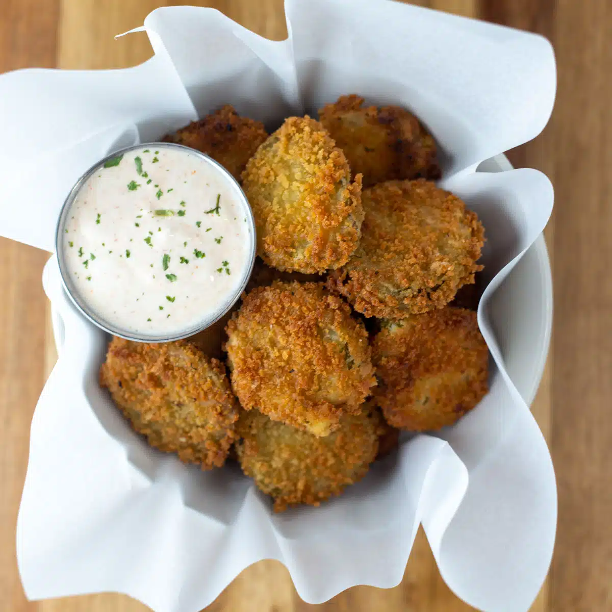 Vierkante afbeelding van gefrituurde augurken met ranch dipsaus.