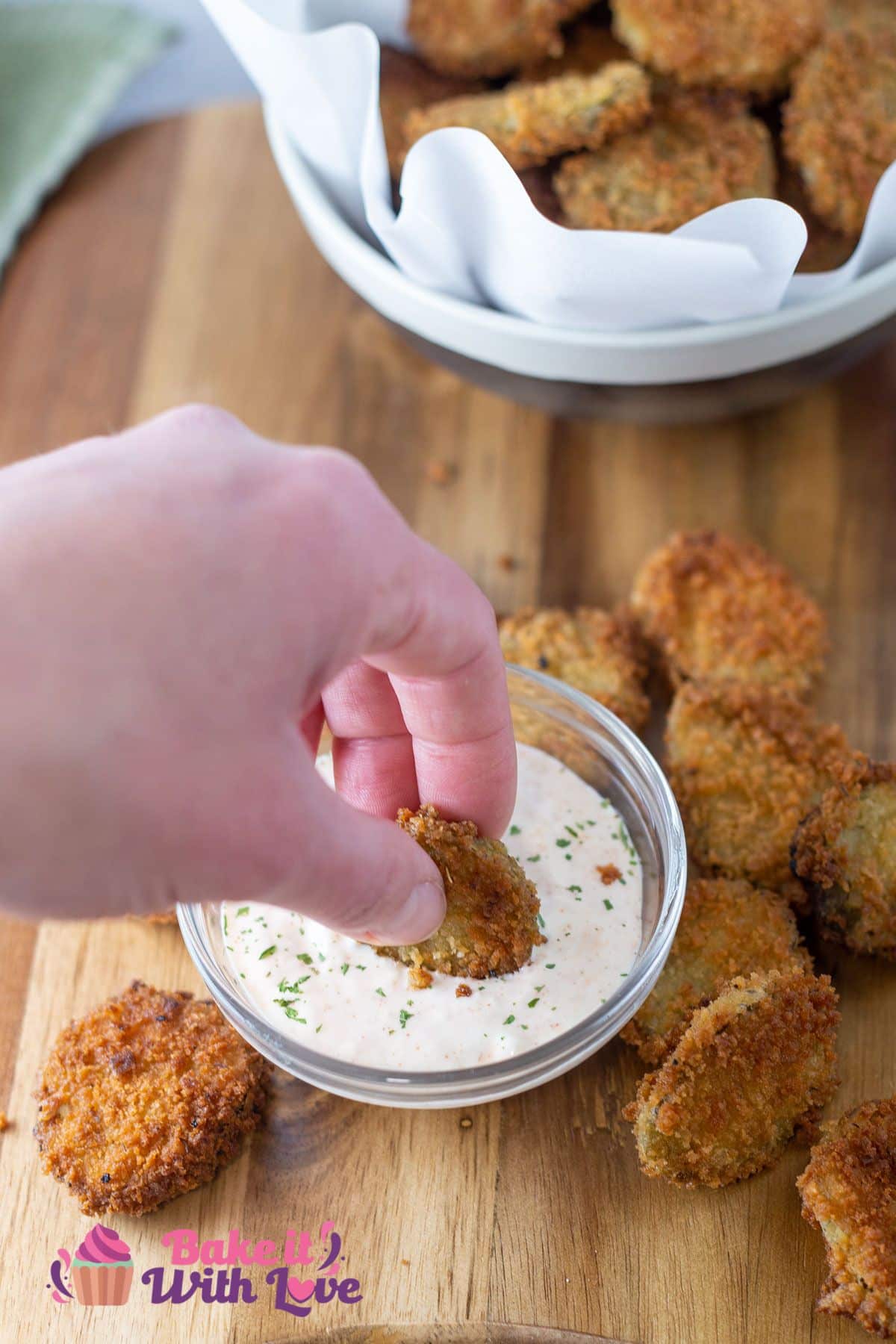 Tall image showing fried pickles being dipped into ranch dipping sauce.