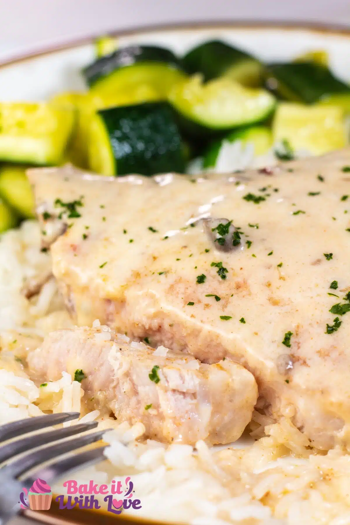 Tall image of cream of mushroom pork chops on a plate over rice with zucchini on the side.
