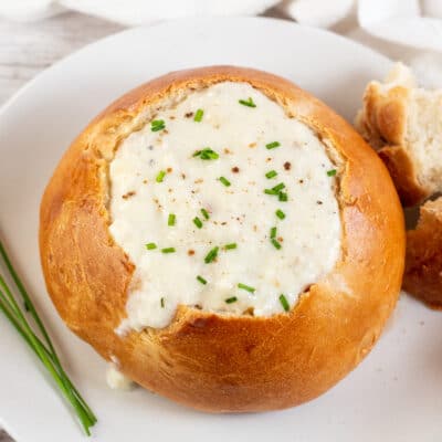 Square image showing a homemade bread bowl filled with soup.