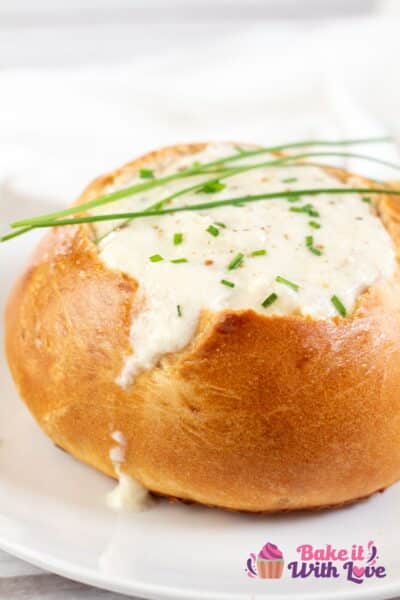 Tall image showing a homemade bread bowl filled with soup.