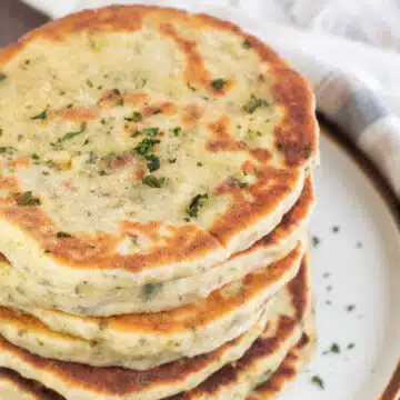 Wide image showing homemade flatbread stacked on a plate.