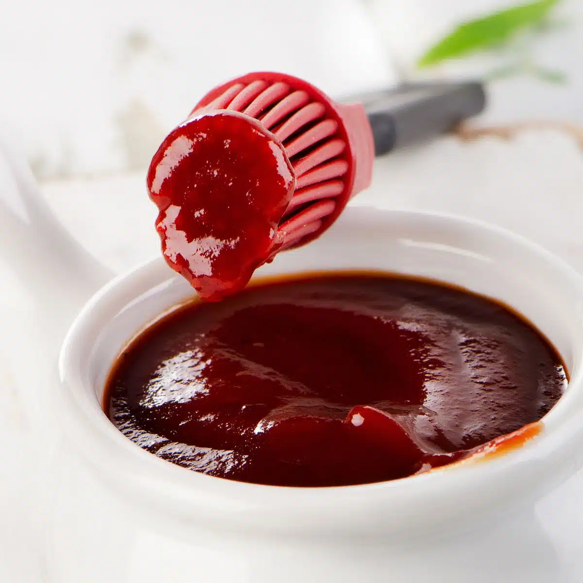 Square image of honey bbq sauce in a small white bowl.