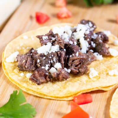 Square image showing slow cooker beef cheek tacos.
