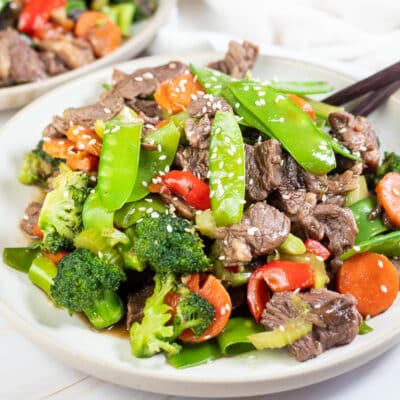 Square image of steak stir fry on a white plate.