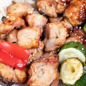 Wide close up image showing chicken teriyaki skewers and veggies.