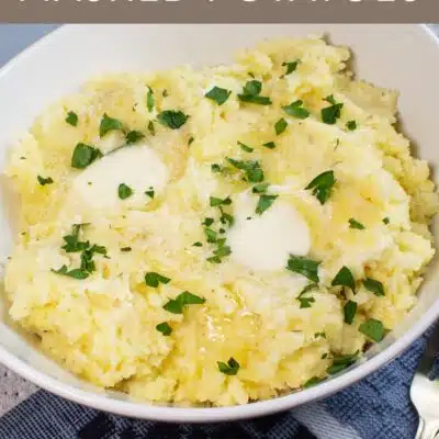 Pin image with text showing cream cheese mashed potatoes in a white bowl with butter and chives.