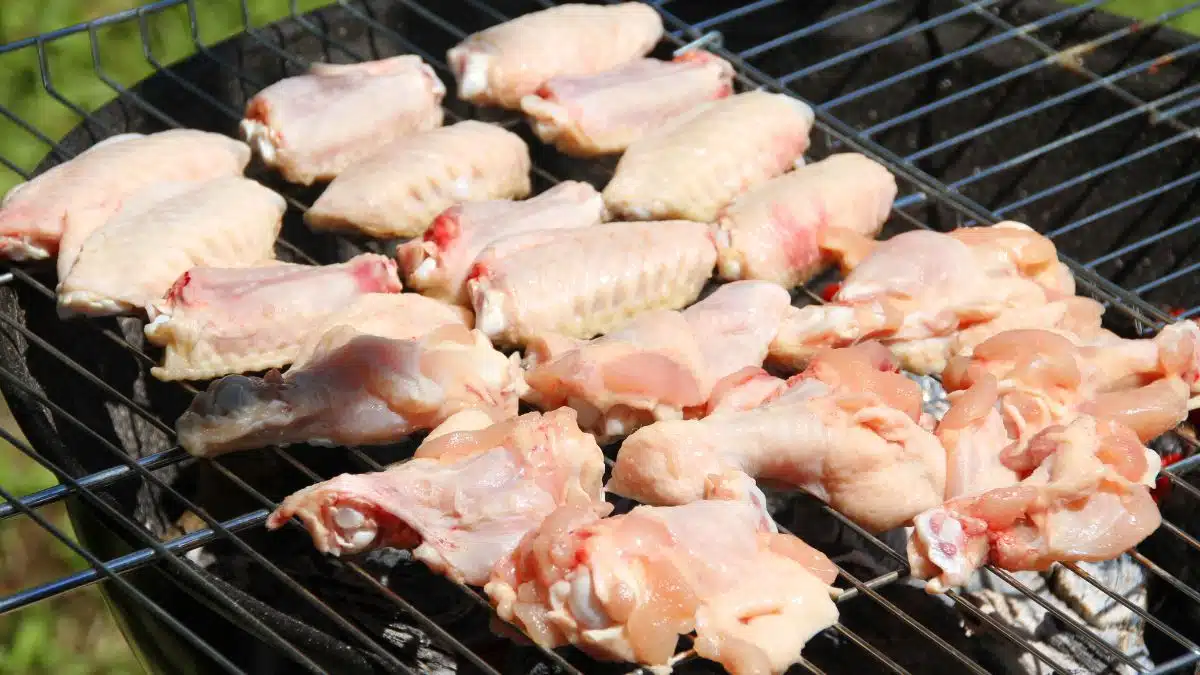 Wide image of grilling raw chicken.