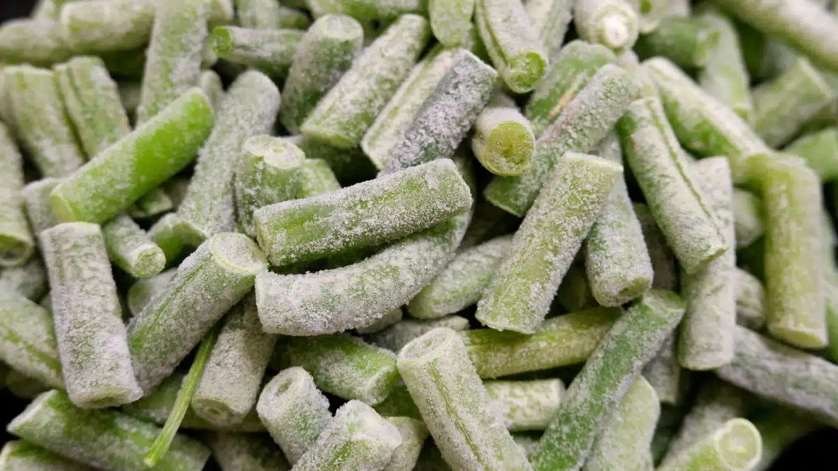 Wide close up image showing frozen green beans.