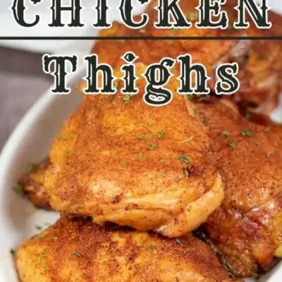 Pin image with text of smoked bone in chicken thighs on a white serving plate.