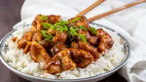 Wide image of peanut butter chicken over rice.