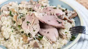 Wide image of a plate of smoked duck risotto with mushrooms.