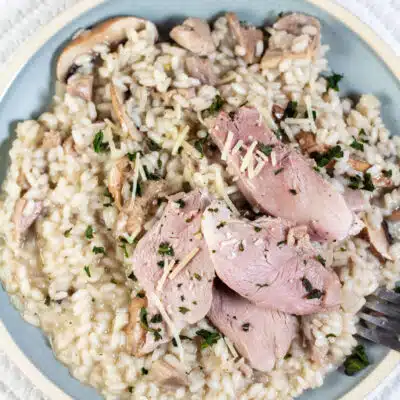 Square image of a plate of smoked duck risotto with mushrooms.
