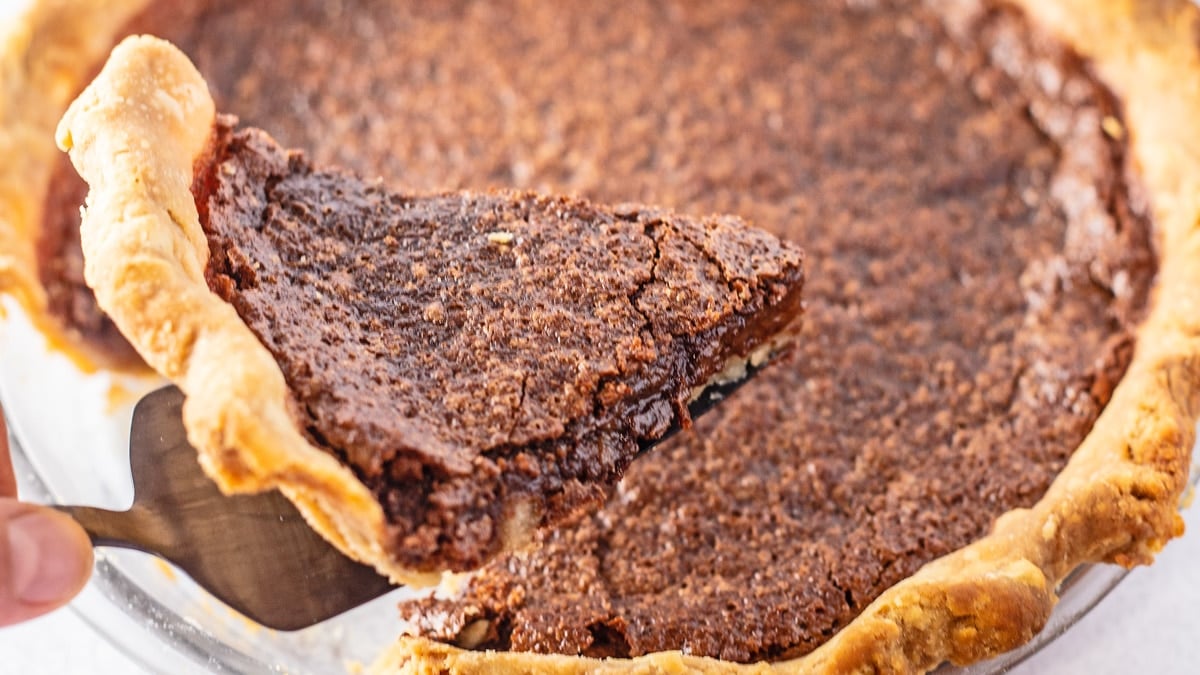 Gambar close up lebar dari sepotong pai coklat.