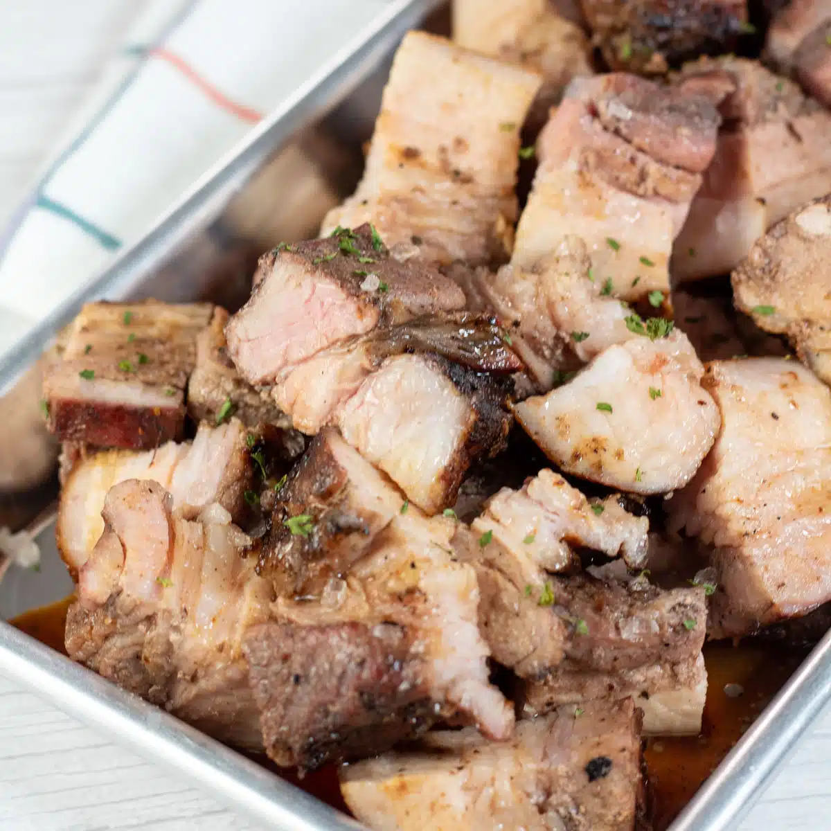 Square image of cut up pork belly.