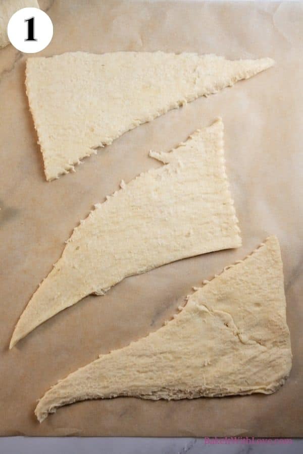 Halloween crescent roll witches hats process photo 1 showing three unrolled crescent roll triangles on a baking sheet. 