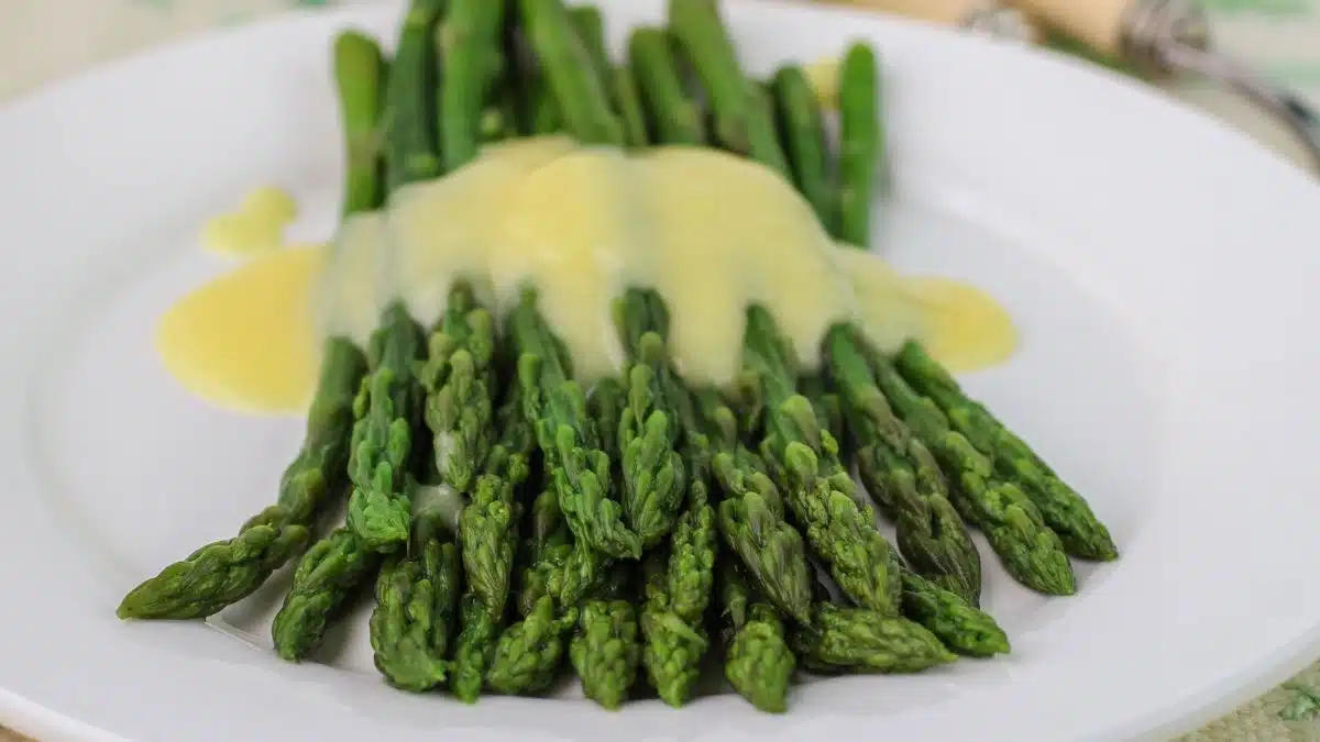 Wide image showing mousseline sauce over asparagus.