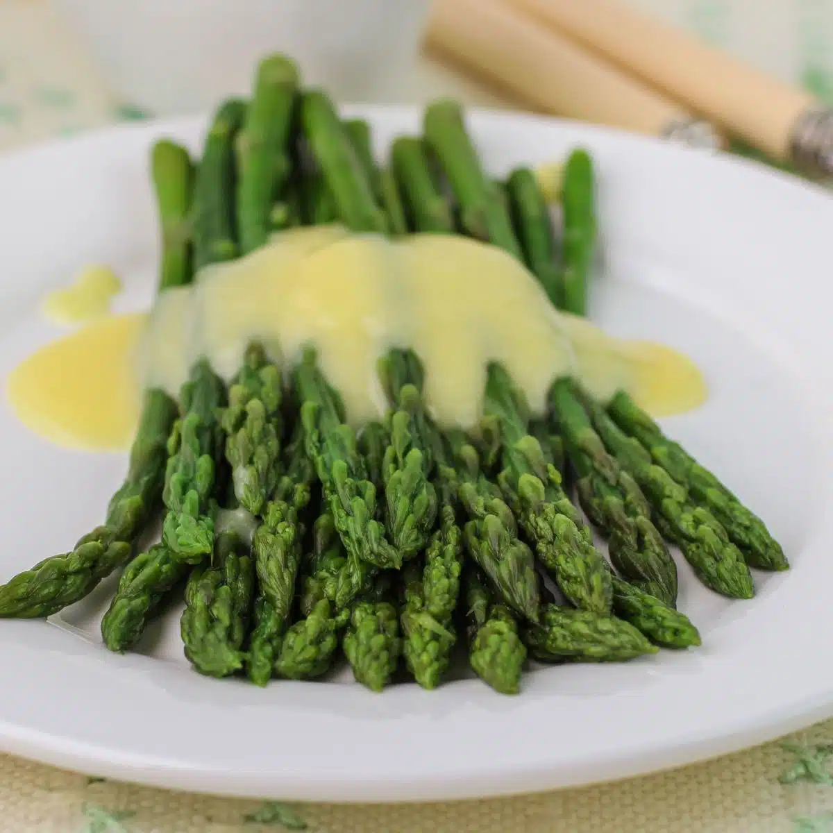 Square image showing mousseline sauce over asparagus.