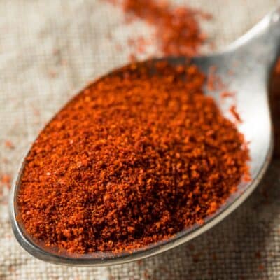 Square image showing paprika spice in a spoon.