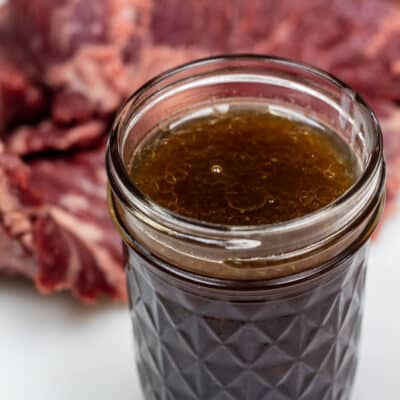 Square image of skirt steak marinade in a glass jar.