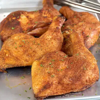 Square image showing smoked chicken leg quarters.