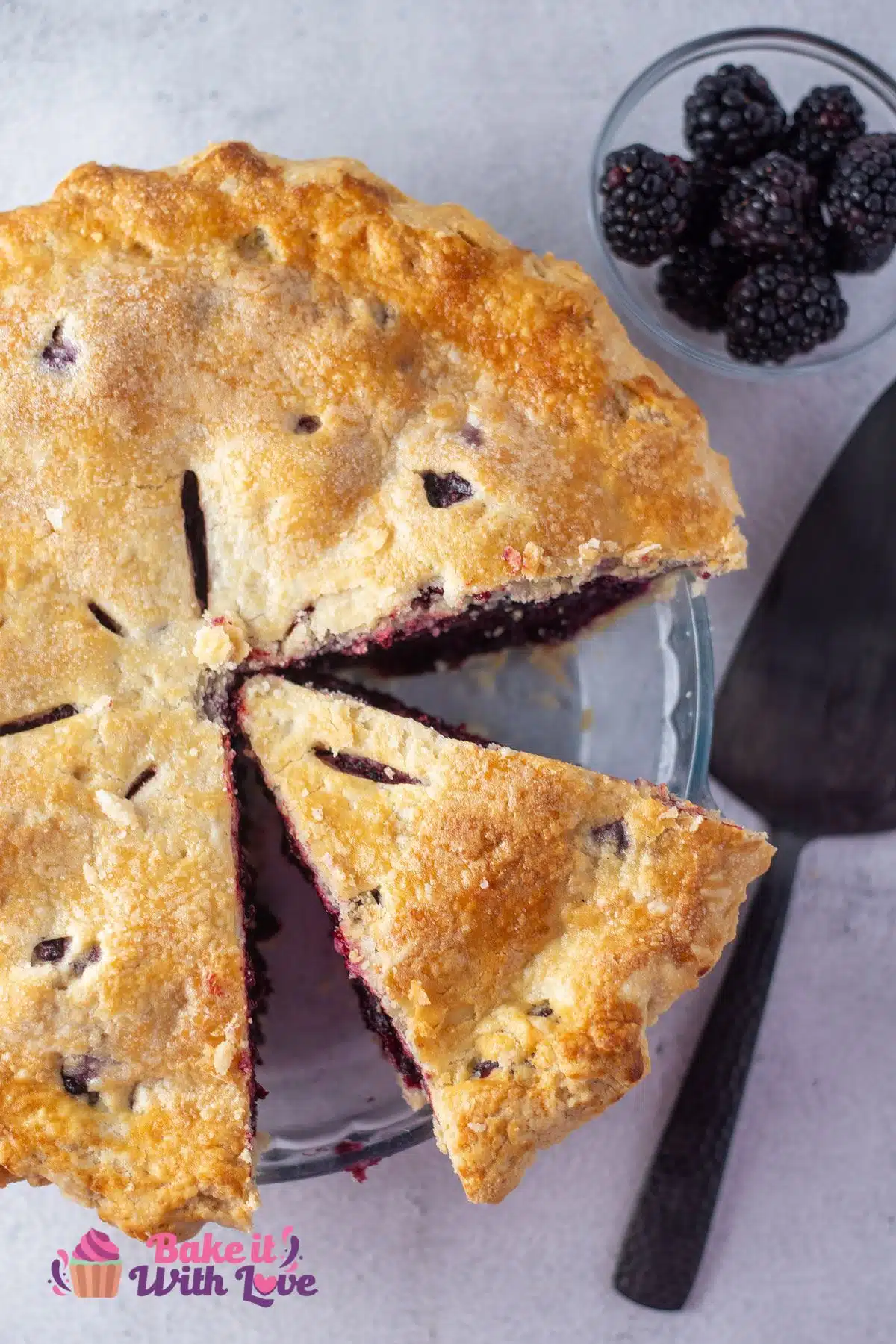 Tall image of blackberry pie whole with slice missing.