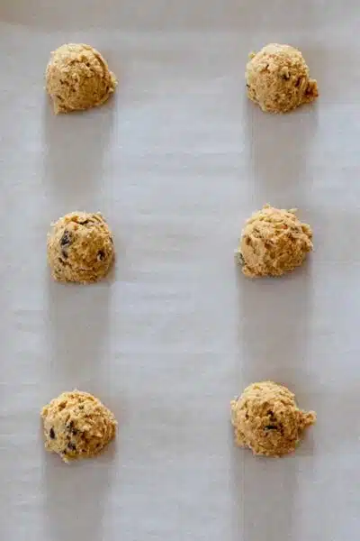 Peanut butter chocolate chip oatmeal cookies process photo 7 portioned cookie dough on parchment paper lined baking sheet.