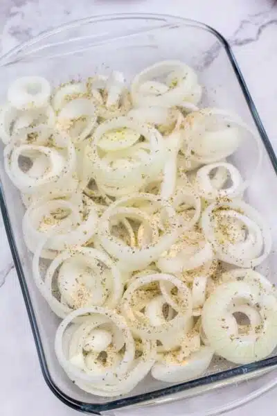 Process image 2 showing seasoned onions in a glass baking dish.