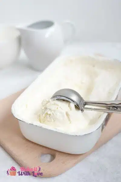 Tall image of no churn vanilla ice cream in a container with scooper.