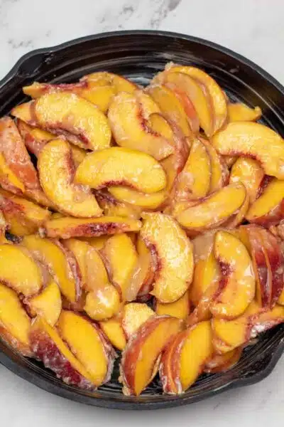 Peach crisp process photo 2 sliced fruit filling mixture in a cast iron skillet.