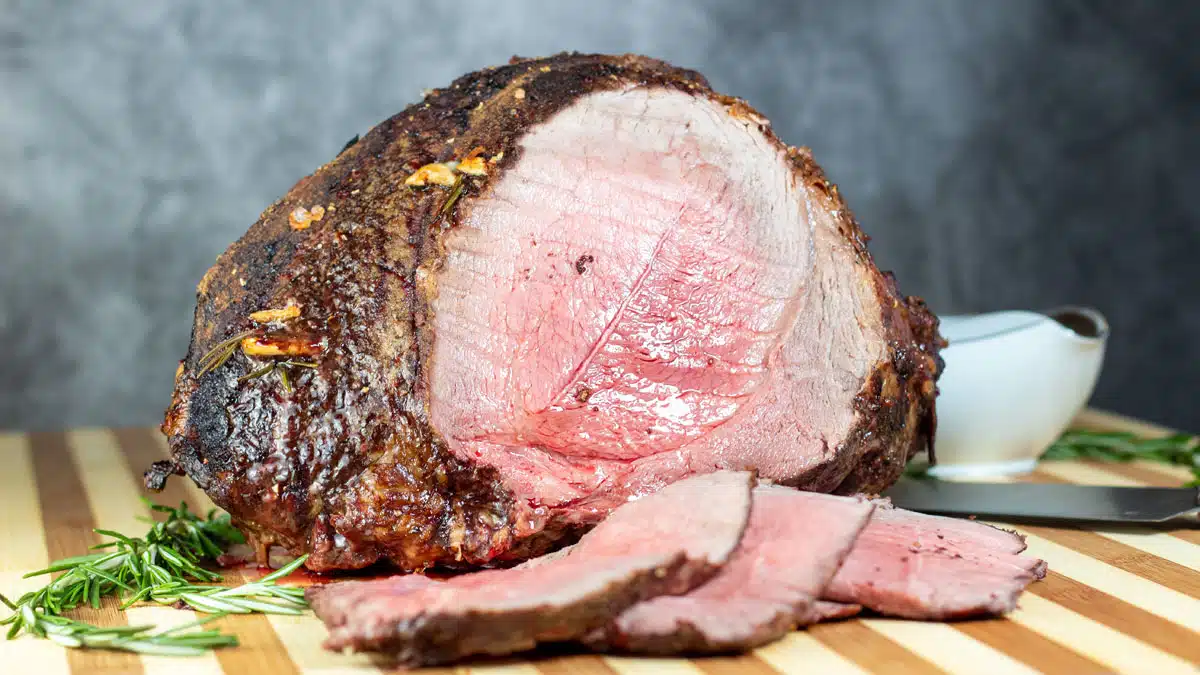 Wide image showing sliced roast beef on a cutting board.