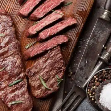 Wide image of sliced Denver steak on a cutting board.