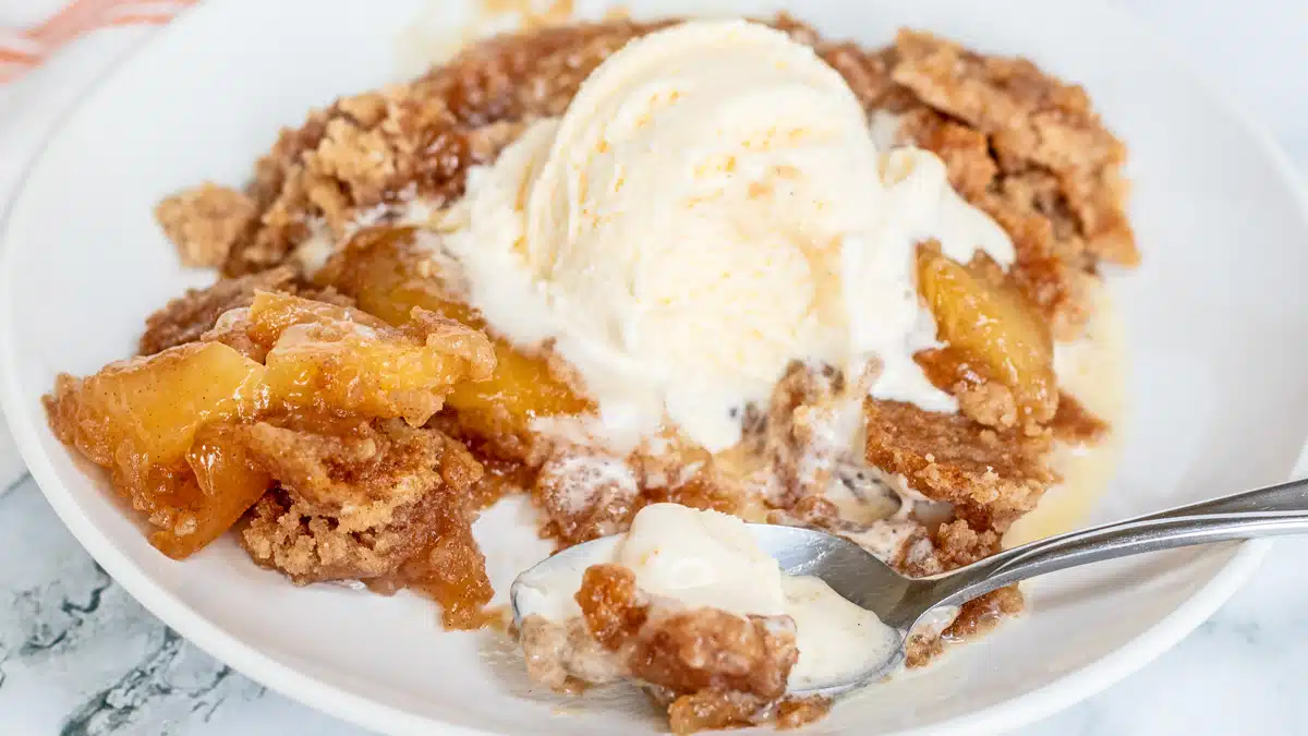 Wide image of apple snickerdoodle dump cake with ice cream.