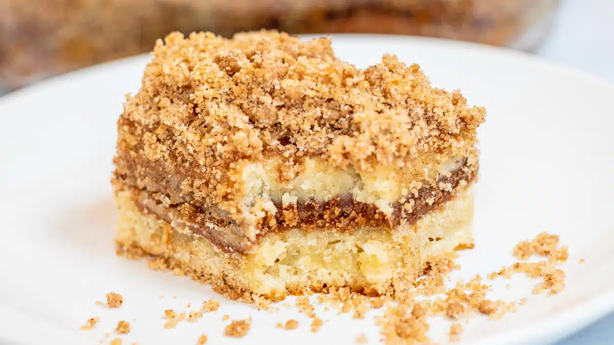 Wide image of slice of sour cream coffee cake on a white plate.