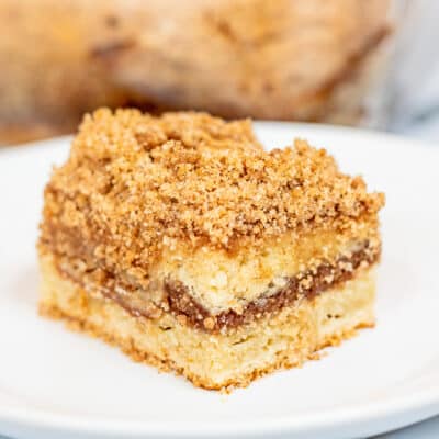 Square image of slice of sour cream coffee cake on a white plate.