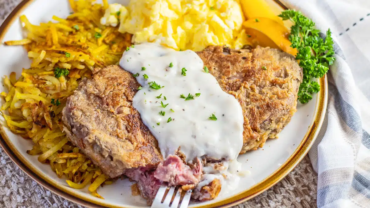 Leftover country fried prime rib breakfast with country gravy showing a slice of the tender roast leftovers cooked to perfection.
