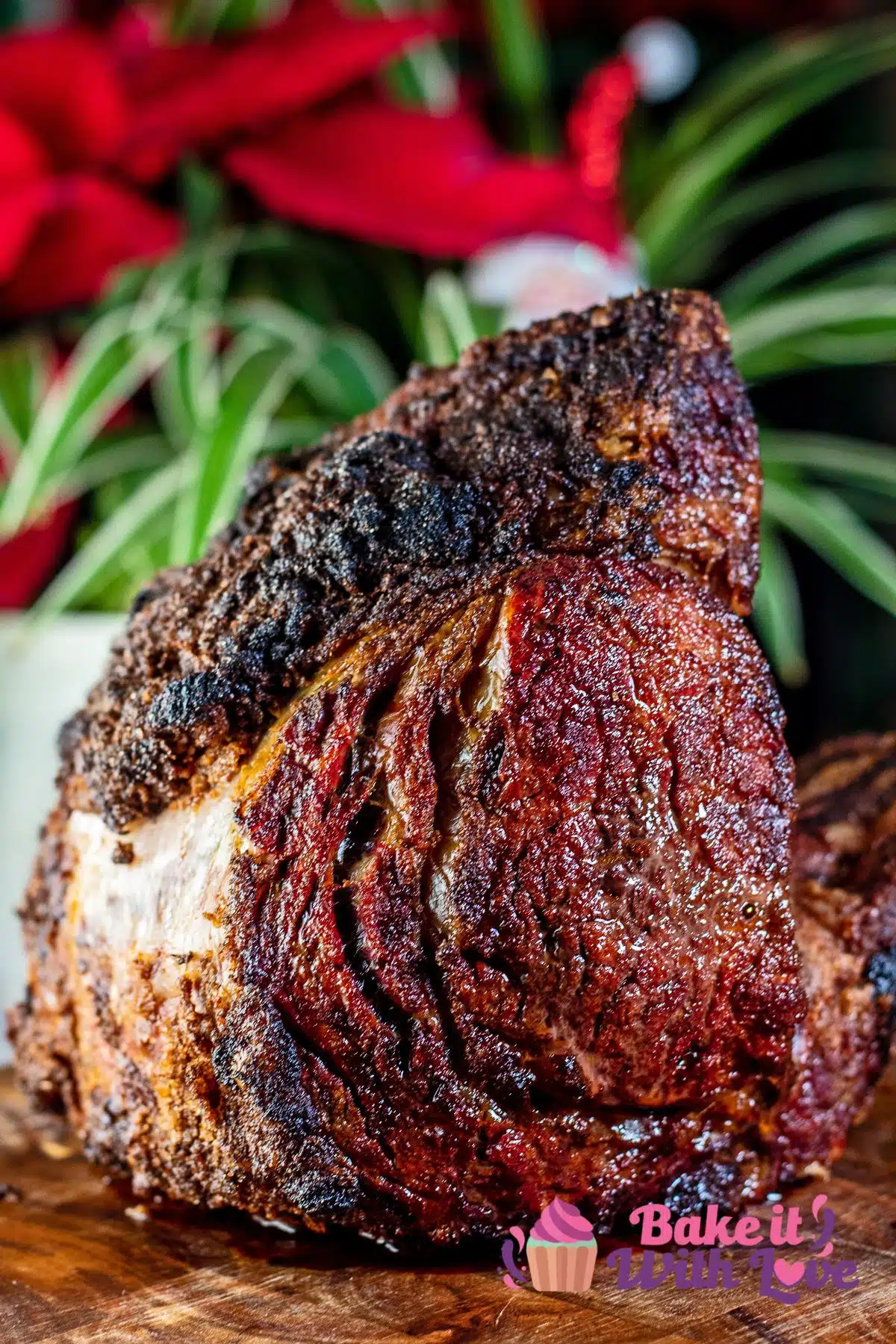 No peek prime rib set upright with holiday centerpiece in the background.