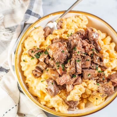 Creamy homemade prime rib macaroni and cheese served in a large tan bowl.