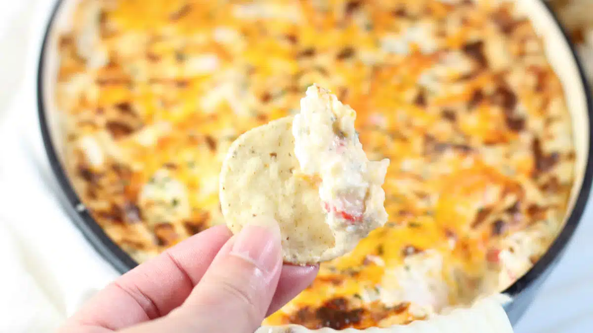 Wide close up image of hot imitation crab dip, and holding chip.