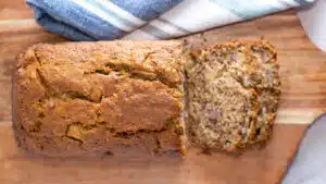 Wide image of apple banana bread sliced on a cutting board.