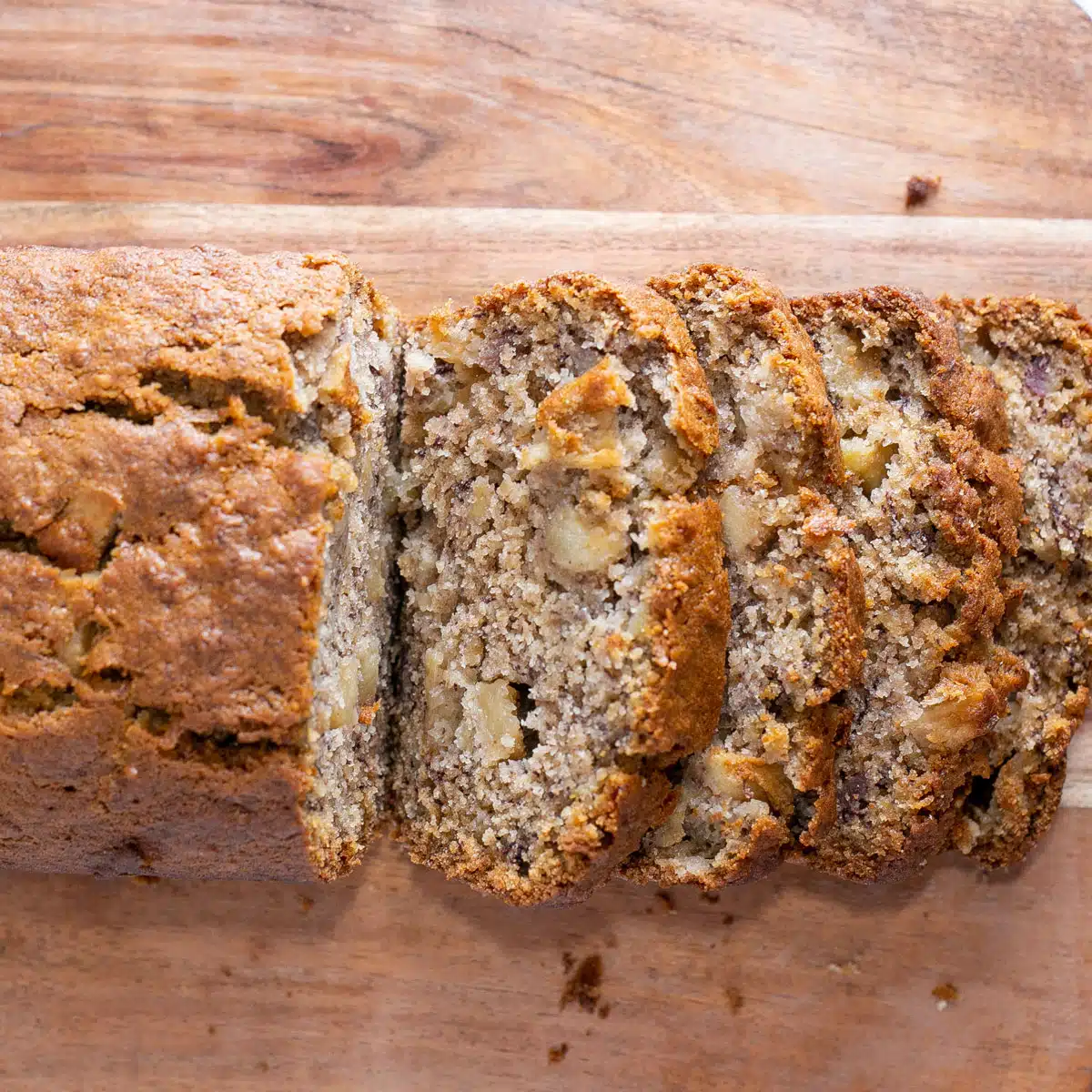 Square image of apple banana bread sliced on a cutting board.