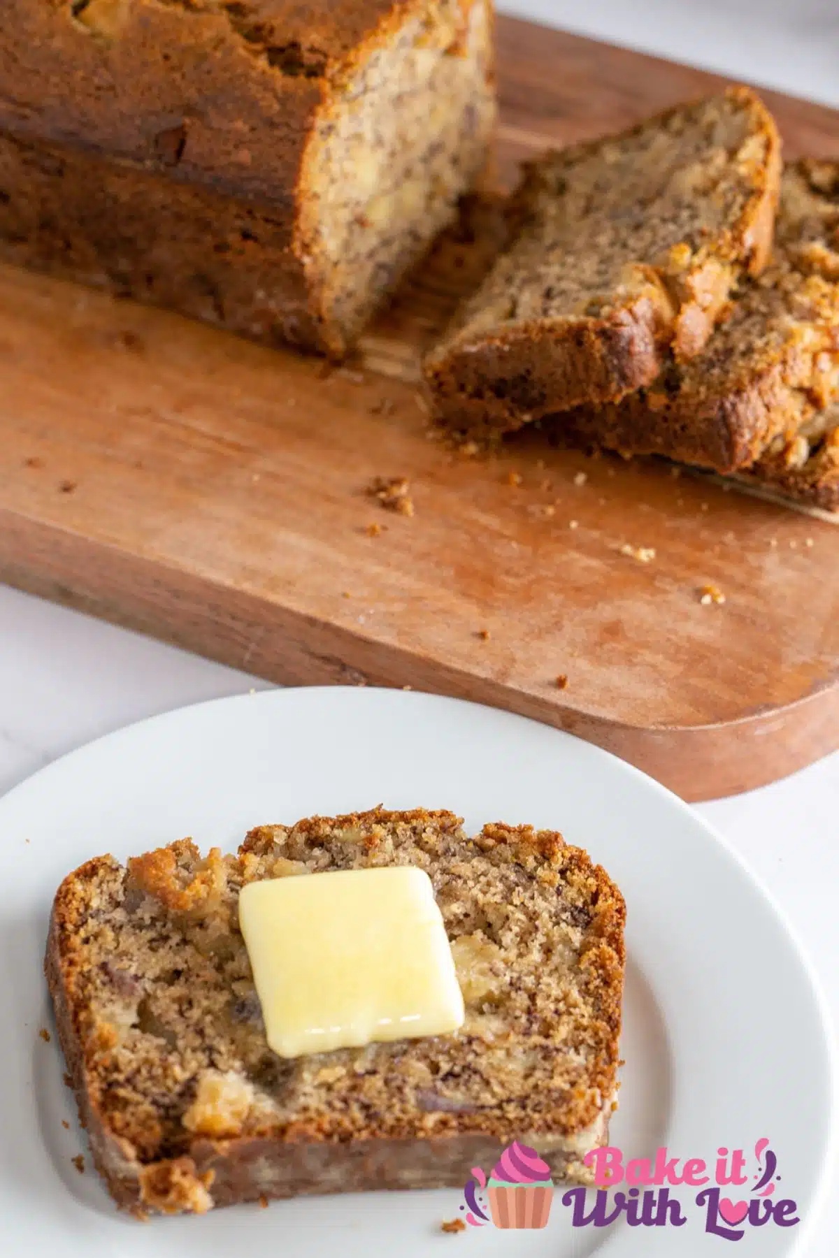 Tall image of apple banana bread, with single slice with pat of butter.