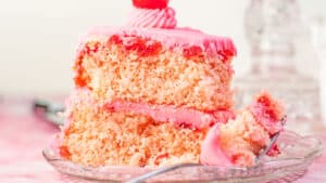 Brede close-upafbeelding van een plakje maraschino-kersencake met de vulling van kersenbotercrème tussen de lagen.