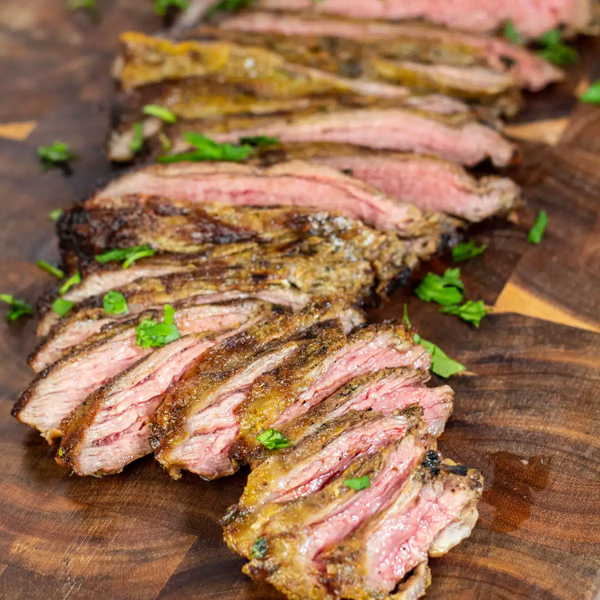 Square image of sliced Arrachera steak on a cutting board.